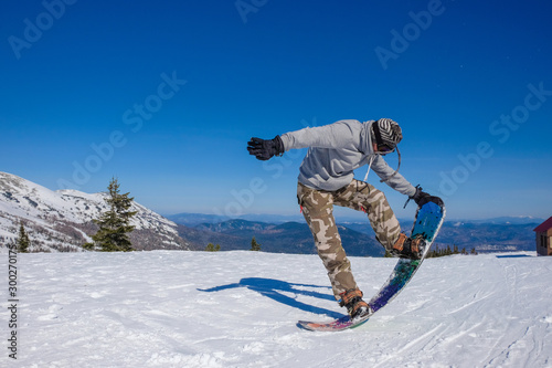 Ski resort. Snowboarder jumping on a snowboard in the mountain. Long jump on a snowboard.