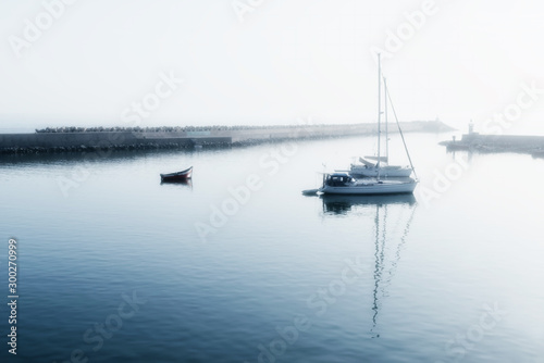 Two sailing boats (yachts) and a small motor boat anchored early morning.
