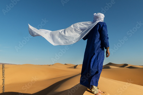 Photo Traditional dressed Moroccan man with turban stands on a sand dune in the Sahara desert