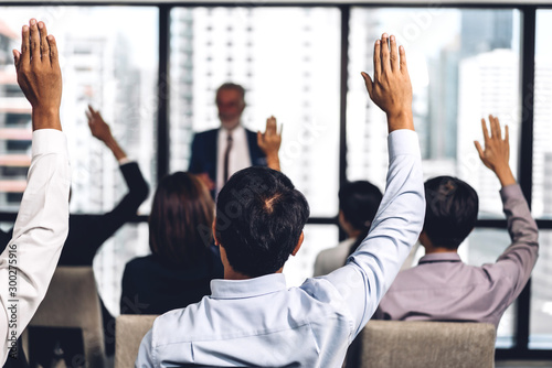 Businessman standing in front of group of people in consulting meeting conference seminar and showing hand to answer question at hall or seminar room.presentation and coaching concept