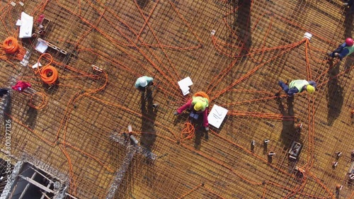 Group of electricians workers installing electric wires on rooftop of building construction. Aerial view.