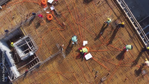 Electricians workers installing electric wires on roof of building under construction. Aerial view.