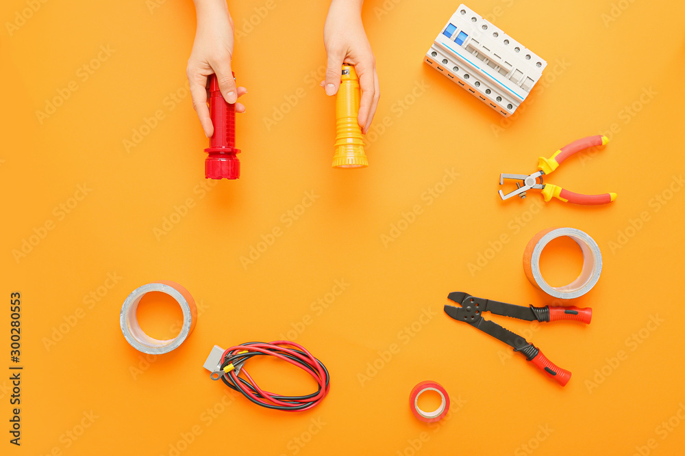 Female hands with set of electrician's supplies on color background Female hands with set of electrician's supplies on color background