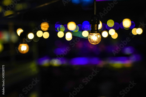 Focus on Vintage circle hanging lamp on the line with blur outdoor concert in the night bokeh background.