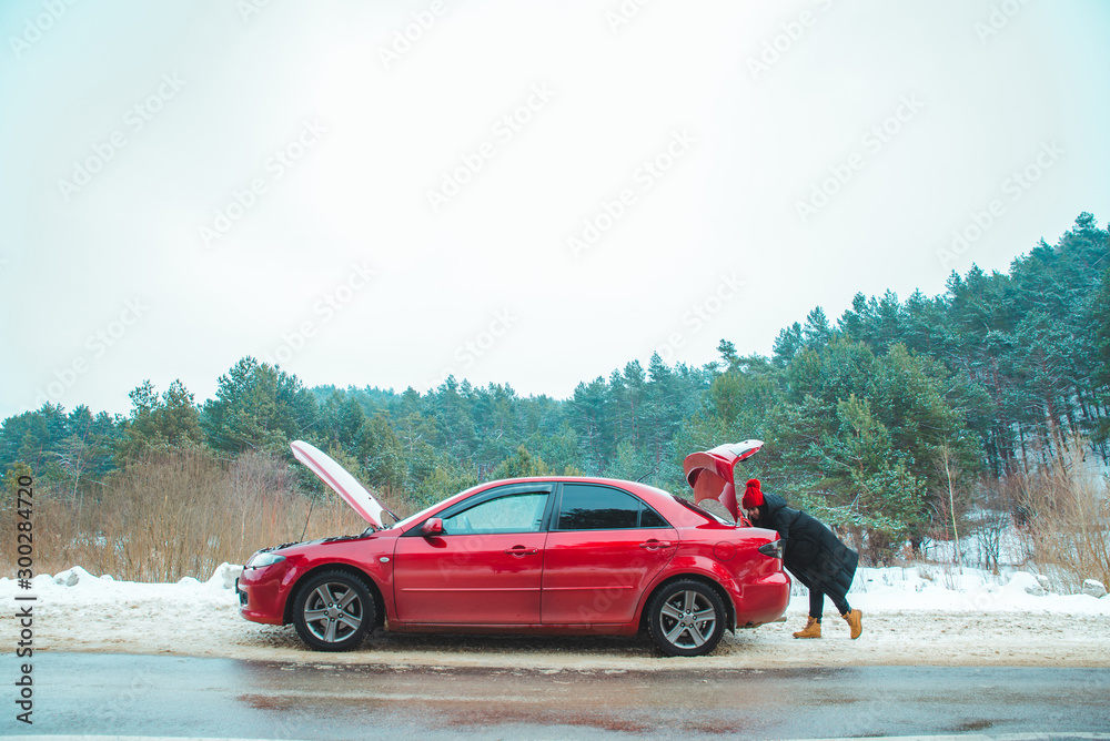 car with opened hood woman looking in trunk