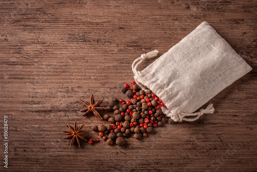 Spices. Black and pink pepper in the sack  on a wooden rustic background.