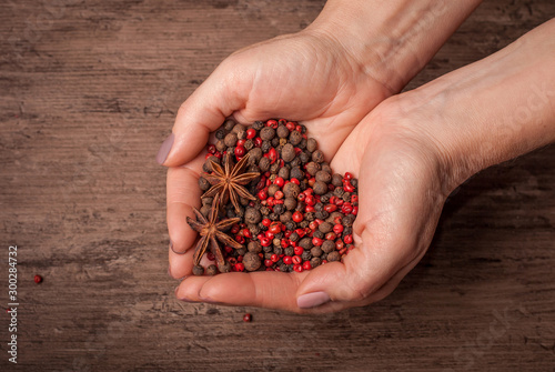 Hands holding the mixture of black and rose pepper in the shape of heart.