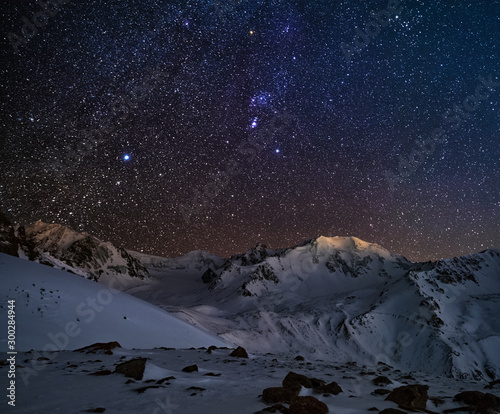 Orion constellation over snow mountain peaks in wintertime