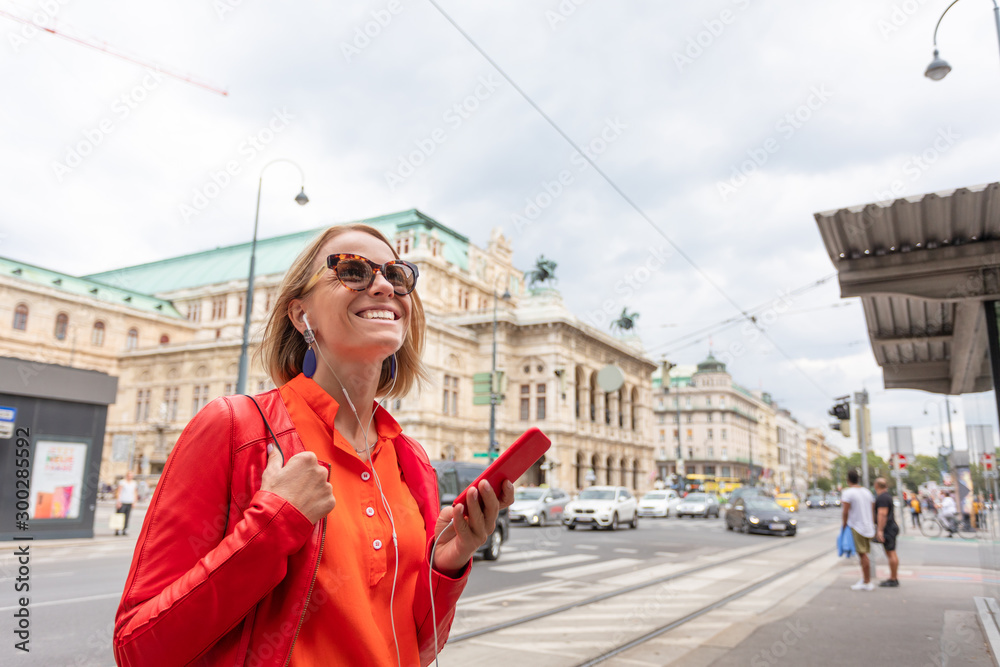 Young girl listens to music with headphones in front of Vienna State Opera, Austria