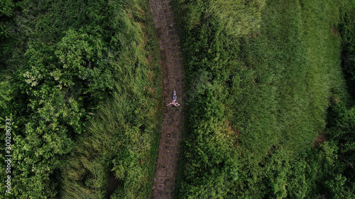Bird's-eye view as a girl runs along a path among green thickets on both sides