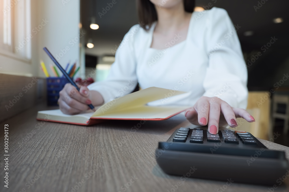 Fototapeta premium woman working with finance calculate on calculator and using notebook in office room.