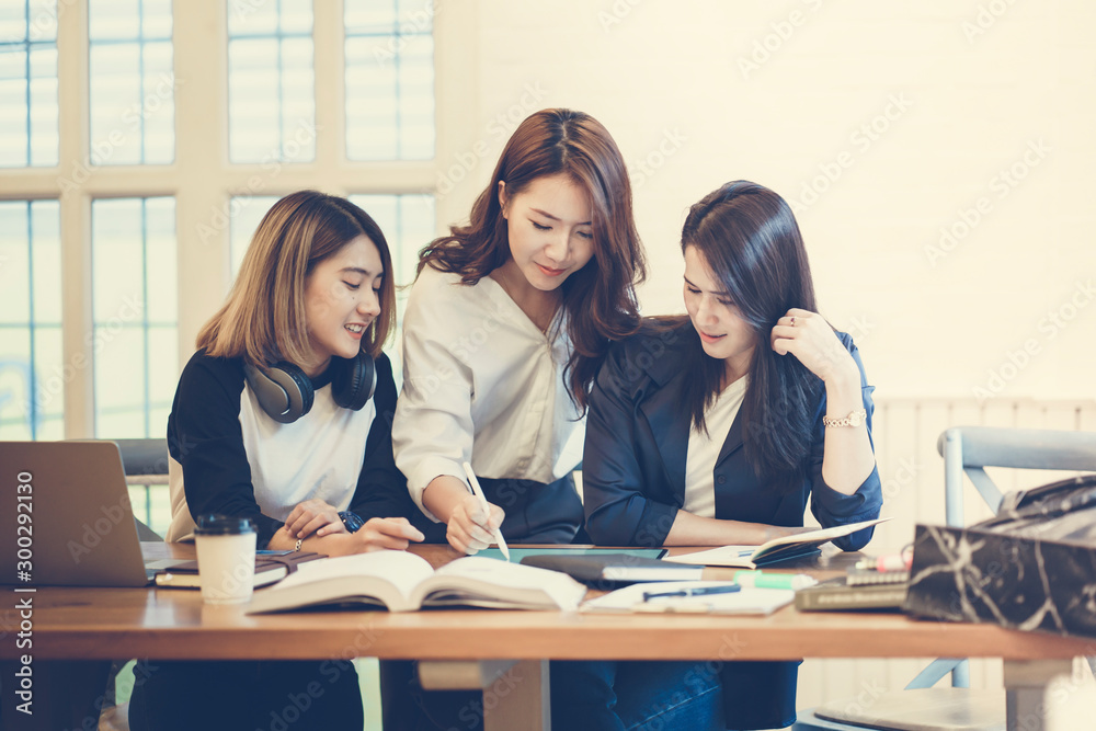College students working with tablet while sitting at table in the library. Young people preparing for class assignment in the university. College students working with tablet while sitting at table in the library. Young people preparing for class assignment in the university.