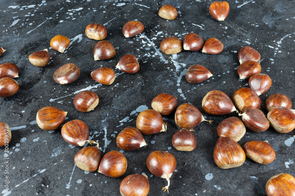 Obraz premium View of some raw chestnuts on a black background with gray moles