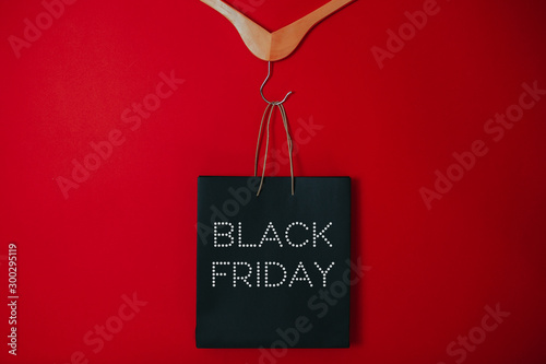Black friday image with space for text. Bkack friday sale flat lay. Black friday bag. Hangers on the red background.