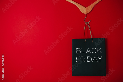 Obraz na płótnie Black friday image with space for text. Bkack friday sale flat lay. Black friday bag. Hangers on the red background. w salonie