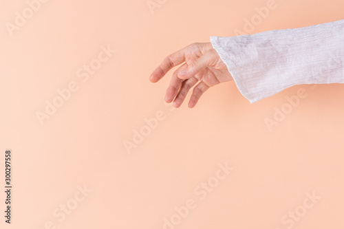 Young Caucasian woman wearing white pure cotton tunic shirt detail of hand sleeve on peachy pink background. Fashion boho style clothes sale poster © olindana