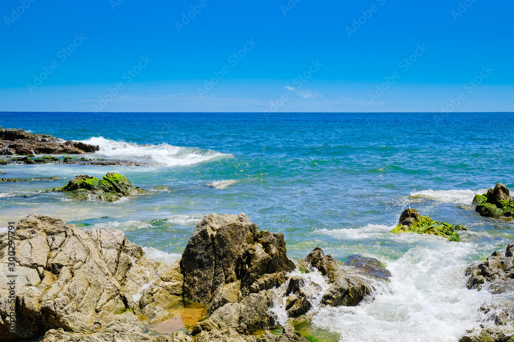 Rocks on the beach near the city beach in Lloret de Mar, Costa Brava. The concept of danger rest. Rocks on the beach near the city beach in Lloret de Mar, Costa Brava. The concept of danger rest.