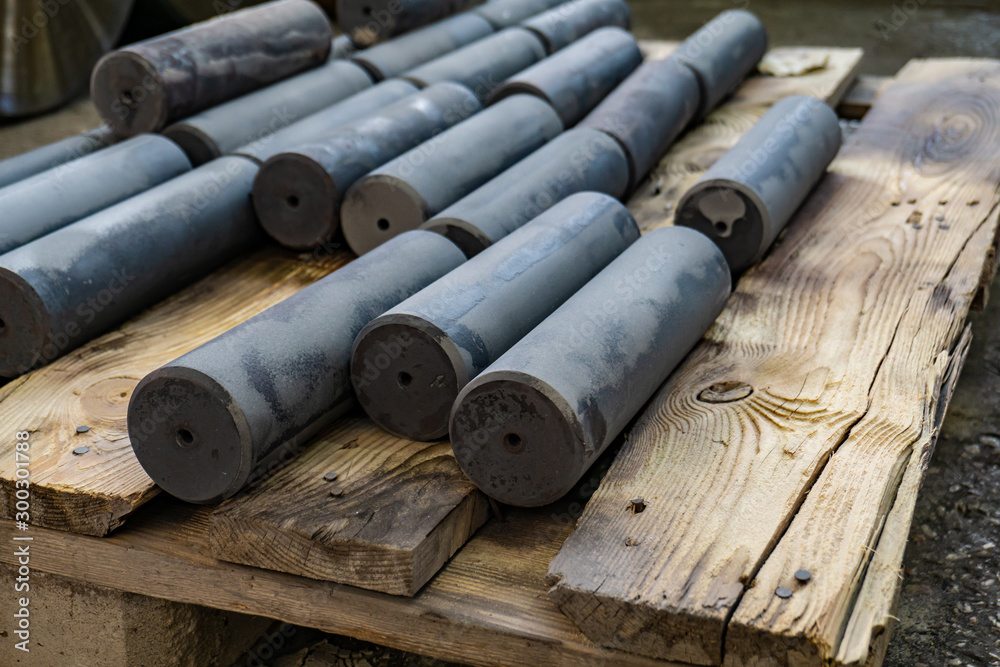 Hardened round blanks for parts after heat treatment lie on a wooden shelf. Hardened round blanks for parts after heat treatment lie on a wooden shelf.