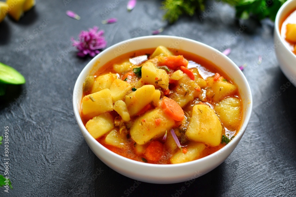 Vegetable stew in a white bowl. Photo food. Stew with potatoes and carrots on a dark concrete background. Healthy vegetarian food. Vegetable stew in a white bowl. Photo food. Stew with potatoes and carrots on a dark concrete background. Healthy vegetarian food.