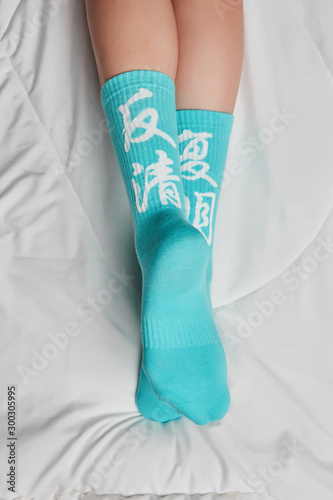 Cropped back view shot of a girl's feet, lying on a white background. It is turquoise socks with white chinese characters on her feet.  photo