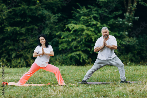 Middle age couple doing yoga standing and making gesture namaste- Concept yoga - Image