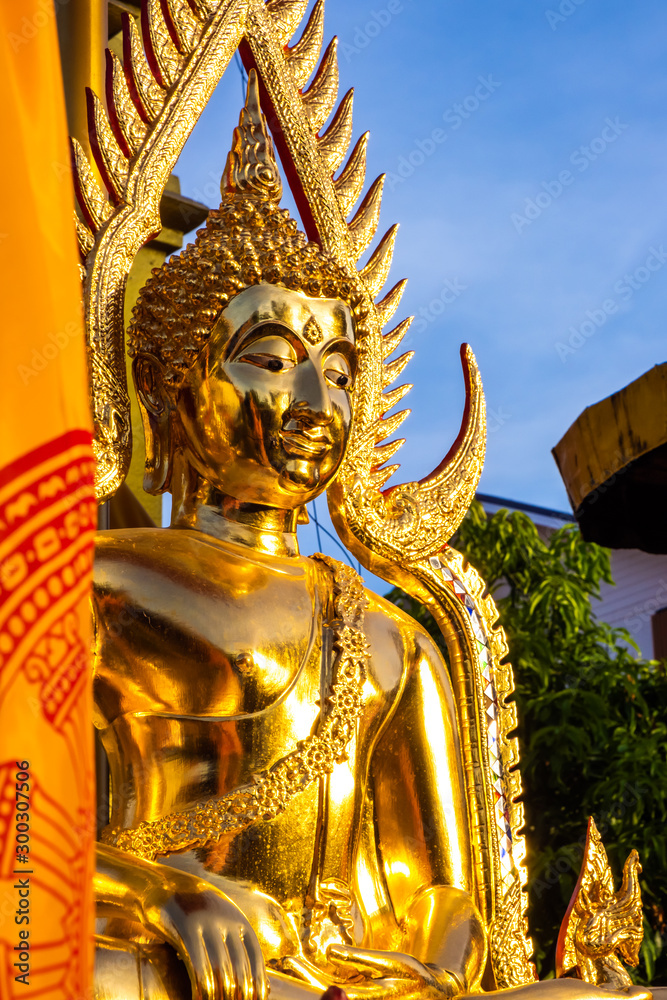 The golden Buddha face in outdoor of the temple in Thailand with the blue sky copy space