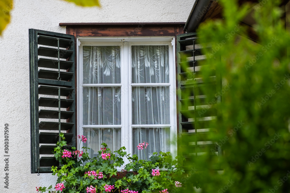 Open Window on the Facade of a white local traditional old House decorated with flower in a European style at countryside village