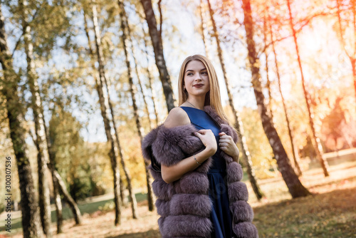 Fashion dresses woman in fur coat and dress posing in autumn park