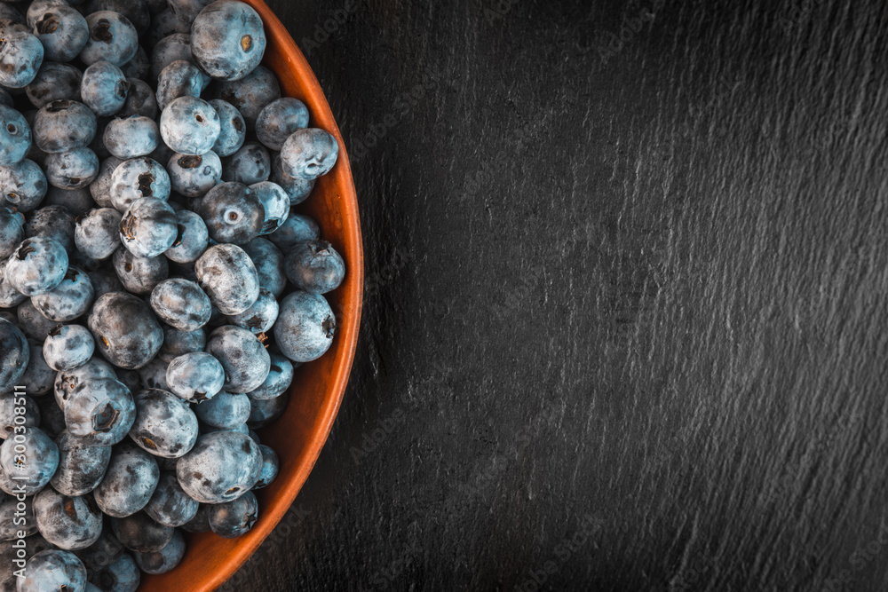 Blueberry heap in the bowl with copy space on a food stone background. Blueberry heap in the bowl with copy space on a food stone background.