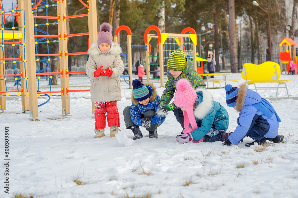 A group of children are playing and having fun on a winter playground. Druzia collect and throw snow. Winter fun. holidays