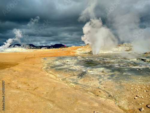 Iceland. Tourists walk around the turmal springs. Steam rises above the hot springs.