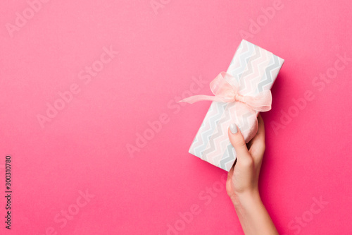 Girl Hands holding craft paper gift box with as a present for Christmas or other holiday on pink background, top view with copy sppace © sosiukin