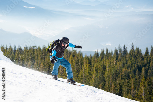 Snowboarder Riding Snowboard in Mountains at Sunny Day. Snowboarding and Winter Sports