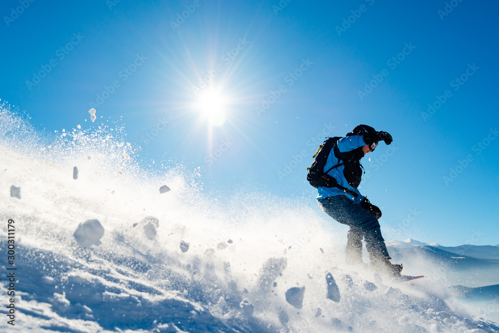 Snowboarder Riding Snowboard in Mountains at Sunny Day. Snowboarding and Winter Sports