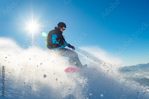 Snowboarder Riding Red Snowboard in Mountains at Sunny Day. Snowboarding and Winter Sports