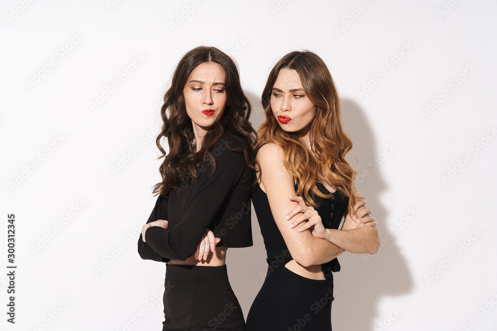 Portrait of two offended women looking at each other while standing back to back Portrait of two offended women looking at each other while standing back to back