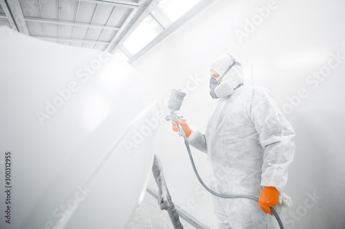 Painting the car in the paint room, spray gun with white paint.