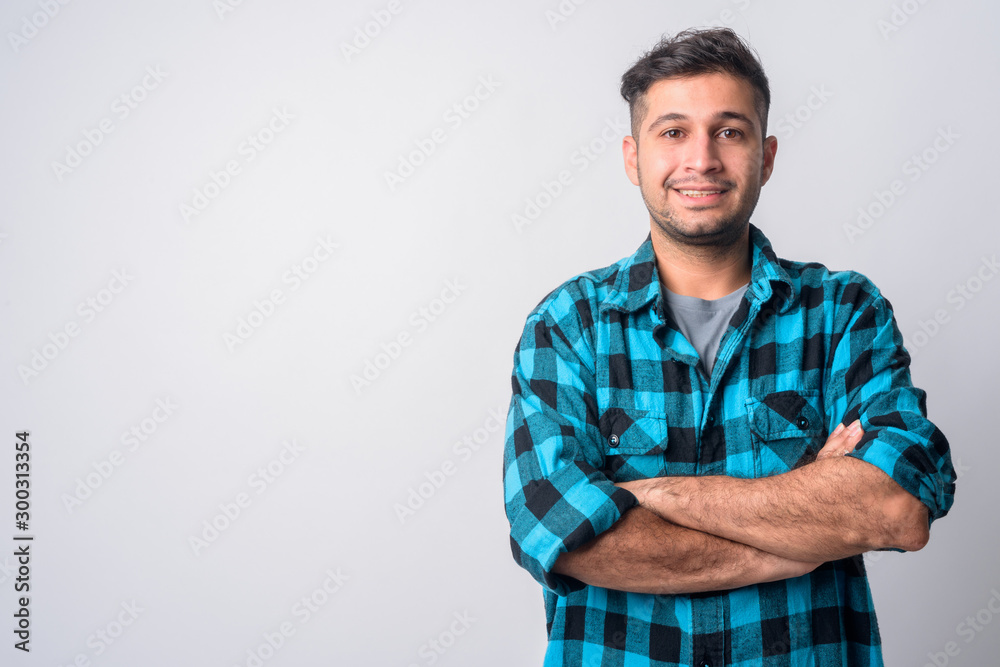 Portrait of happy young Persian hipster man smiling with arms crossed