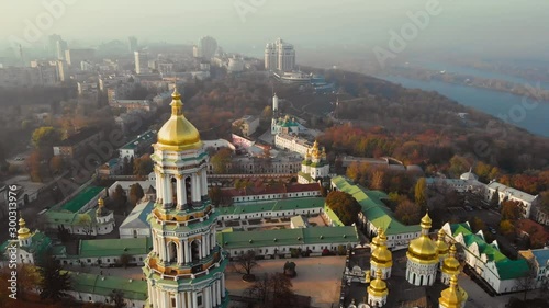 Kiev Pechersky Monastery on sunset fog sky and modern Kiev City background. Archutecture Kiev Pechersk Lavra on evening city landscape. Camera moves forward. Aerial view, drone video footage. photo