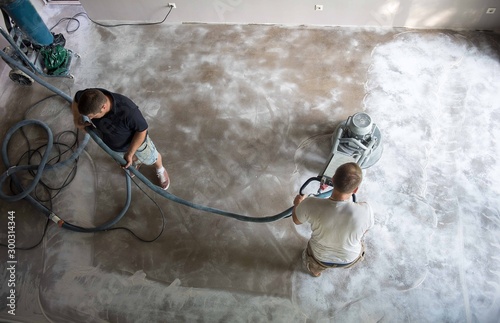 Construction worker in a family home living room that grind the concrete surface before applying epoxy flooring.Polyurethane and epoxy flooring.Concrete grinding. photo