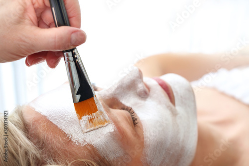 The beautician puts a silver mask on the woman's face