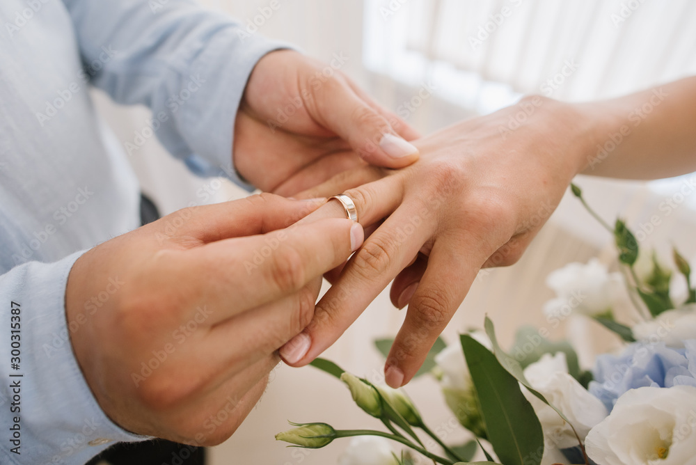 Groom wearing bride wedding ring on her finger closeup