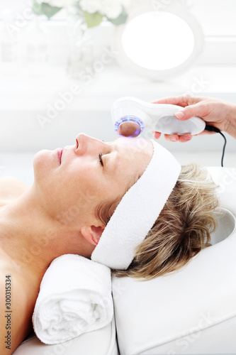 Photonic ultrasonic facial massage. Ultrasonic facial massage using light therapy. Professional treatment in a cosmetics clinic.