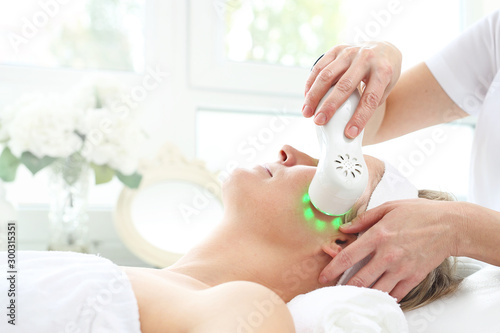 Ultrasonic facial massage, light phototherapy. Ultrasonic facial massage using light therapy. Professional treatment in a cosmetics clinic. photo