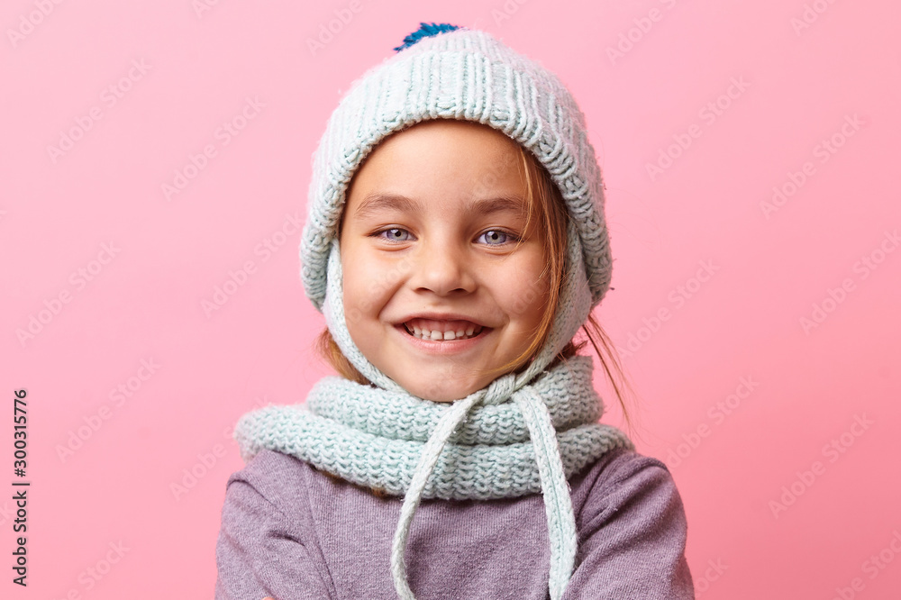 Close up portrait of smiling little girl in winter cap and scarf on pink background. Close up portrait of smiling little girl in winter cap and scarf on pink background.