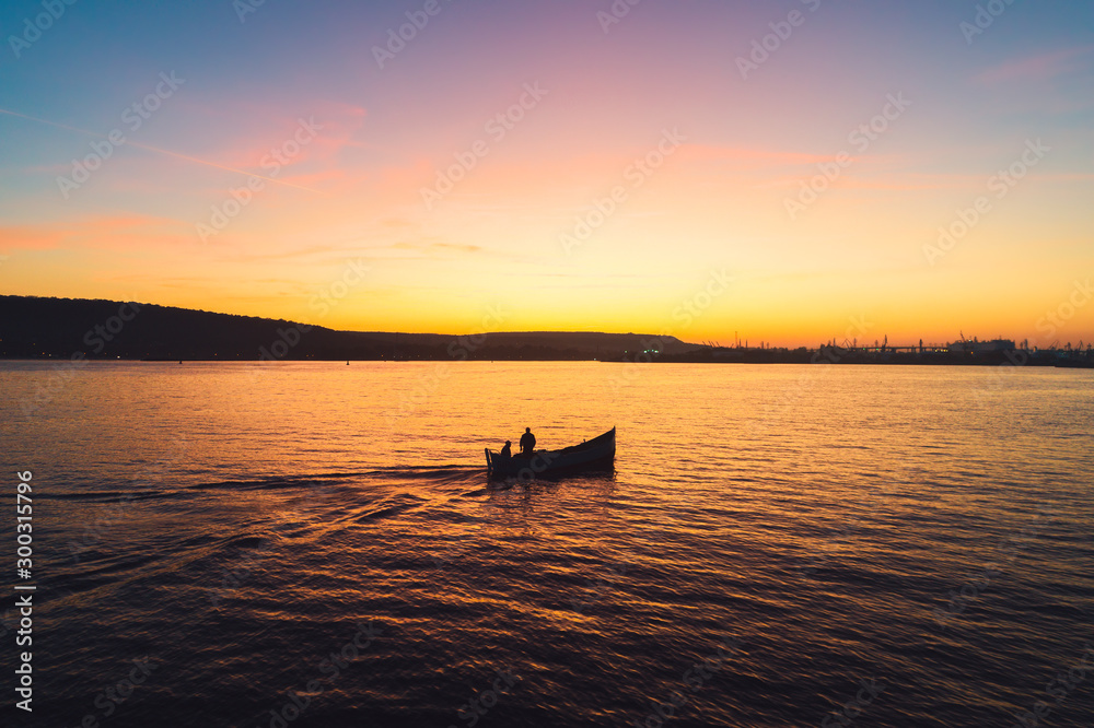 Sunset over fishing boat and shining golden sea water