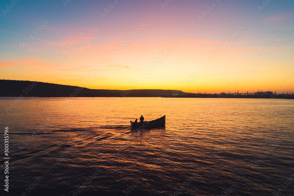 Obraz premium Sunset over fishing boat and shining golden sea water