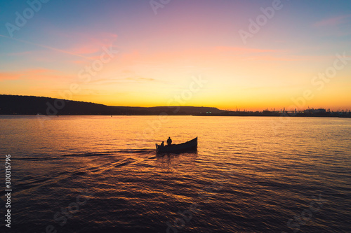 Sunset over fishing boat and shining golden sea water