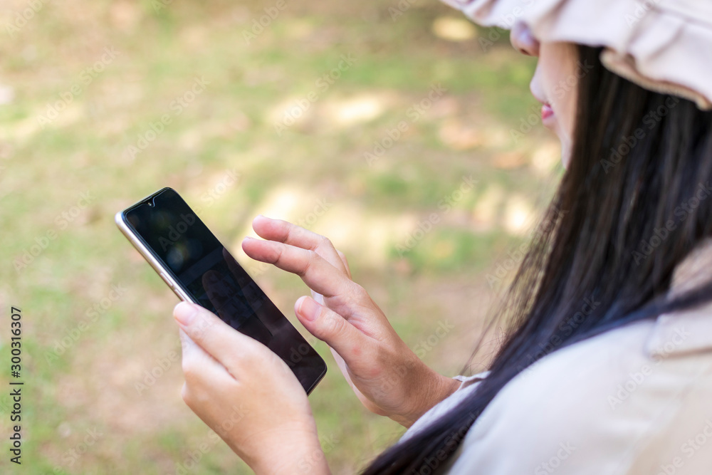 Young happy woman using smartphone. Beautiful smiling woman use of mobile phone in public park. Young happy woman using smartphone. Beautiful smiling woman use of mobile phone in public park.