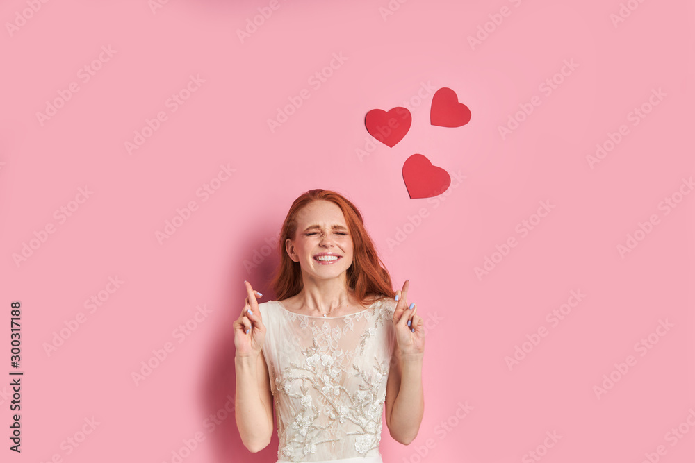 Young caucasian woman in white wedding dress dream and hope about husband with closed eyes, red hearts above her head. Love and people concept